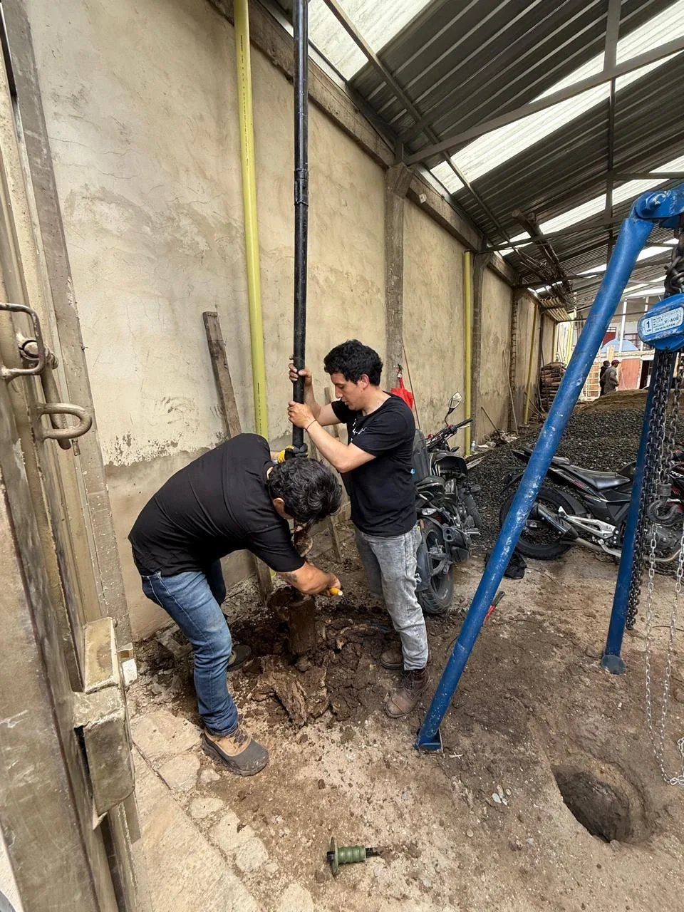 Dos trabajadores realizan exploración del terreno junto a un equipo de perforación
